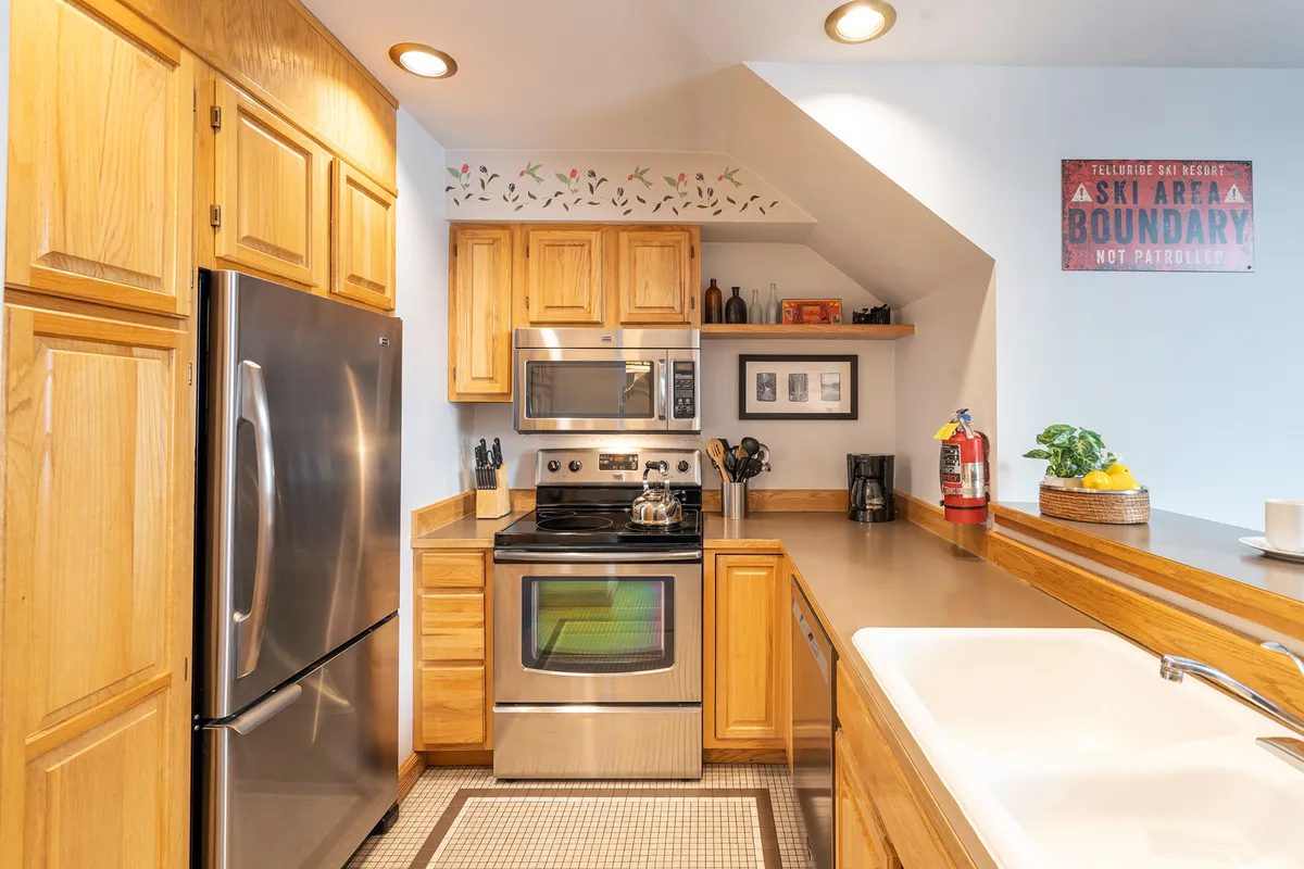A modern kitchen featuring stainless steel appliances, wooden cabinetry, and a decorative wall trim. A fruit bowl on the counter adds a homely touch. The kitchen is well-equipped and ready for preparing anything from quick breakfasts to festive dinners, encouraging culinary creativity and shared moments.